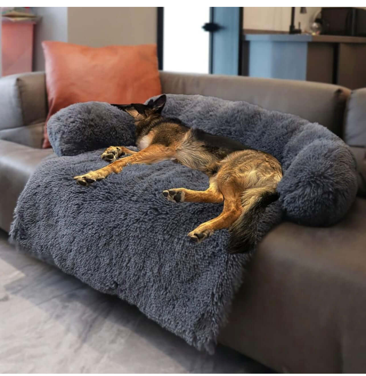 Large dark grey calming dog bed with plush fabric, providing comfort and head support for a peacefully sleeping dog.