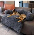 Large dark grey calming dog bed with plush fabric, providing comfort and head support for a peacefully sleeping dog.